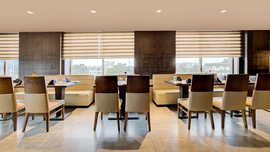 Spacious dining area with modern furnishings and large windows allowing natural light at Voyage Milestone Hotel and Banquet Siliguri