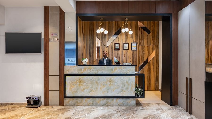  A hotel reception area with a well-designed desk with suited man standing behind the desk , wood-panelled walls and soft lighting, offering a pleasant check-in experience - Clarks Inn Express, Near Jammu Bari Brahmana Railway Station