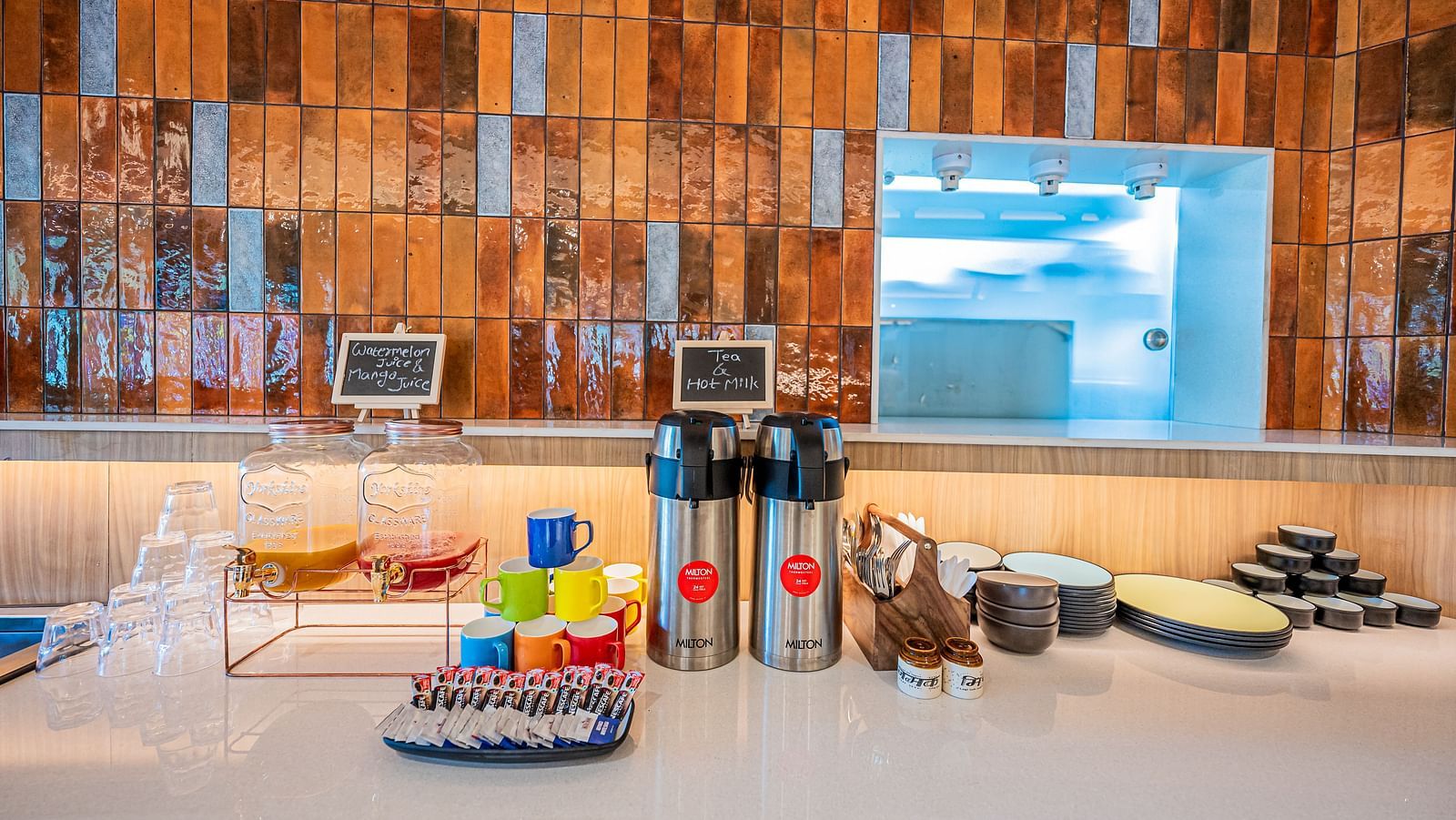 A close-up view of the kitchen counter at Indie Stays Mumbai International Airport, with cups, bottles, and essentials neatly placed on top.