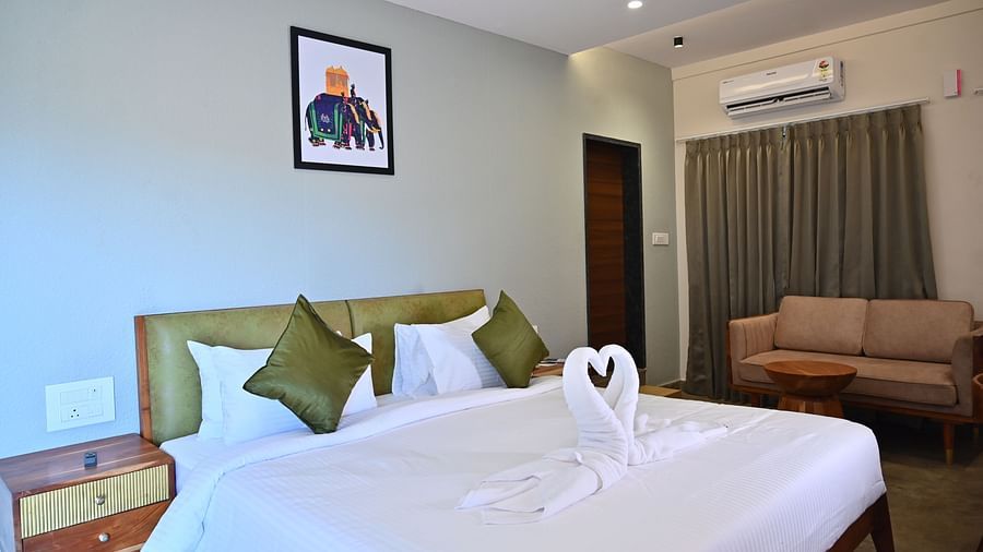 Club Suite featuring a large bed with pillows, a towel swan, a sofa, and warm wooden furniture at TGI Livancia Hillside