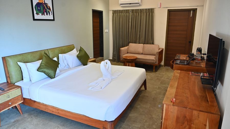 Spacious suite with a large bed, pillows, a sofa, and a wooden desk with modern amenities at TGI Livancia Hillside