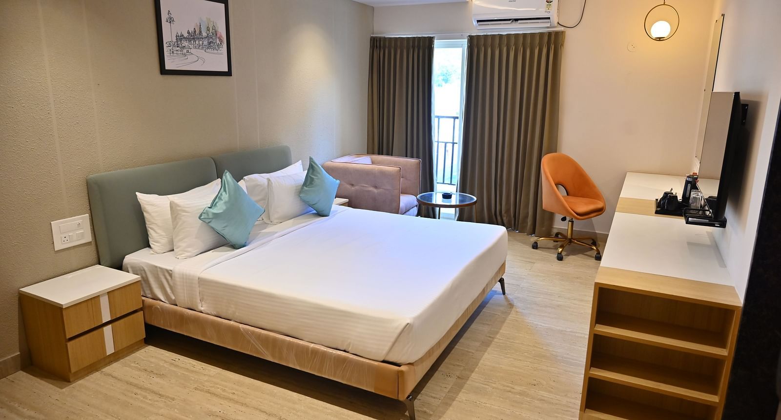 Bright and airy premium room with a big bed, soft chairs, and curtains over large windows, offering plenty of light and modern features at TGI Livancia Hillside