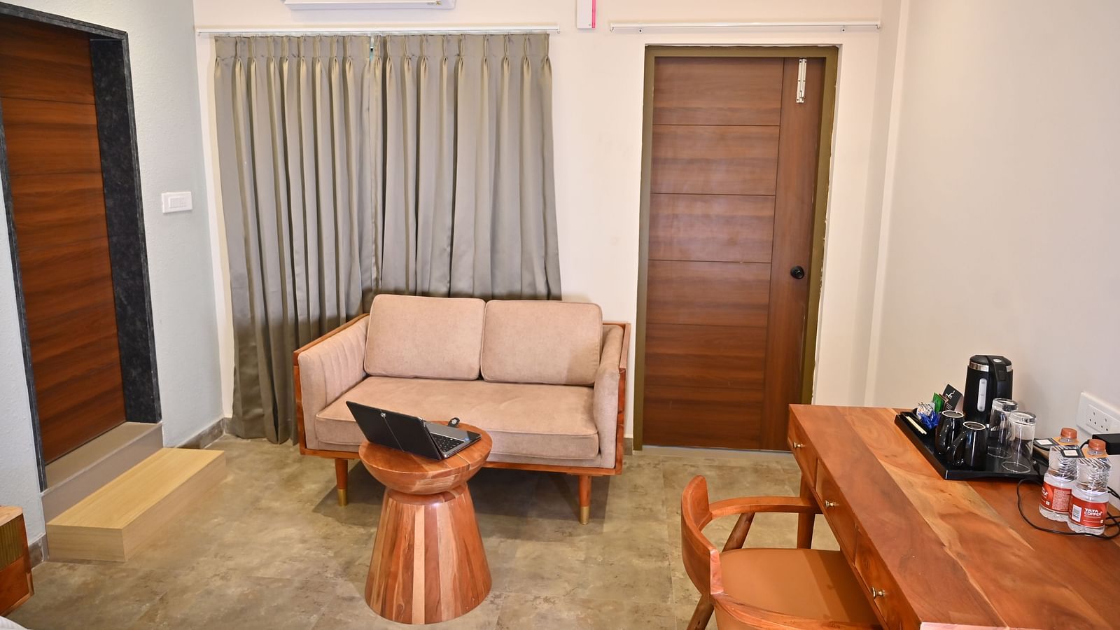 Cosy seating area in a room with a sofa, a wooden coffee table, a wooden desk with a chair, and a tea and coffee setup at TGI Livancia Hillside