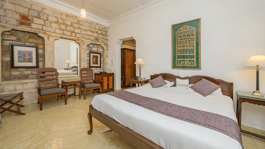 Double bed, stone accents, and wooden chairs in Samarjit Vilas at Deo Bagh - 17th Century, Gwalior.