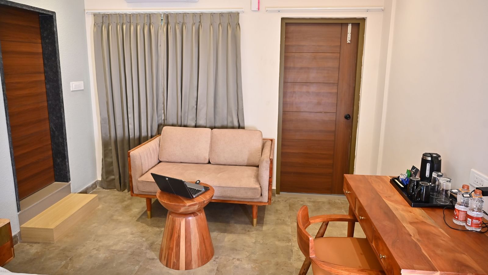 Cosy seating area in a room with a sofa, a wooden coffee table, a wooden desk with a chair, and a tea and coffee setup at TGI Livancia Hillside