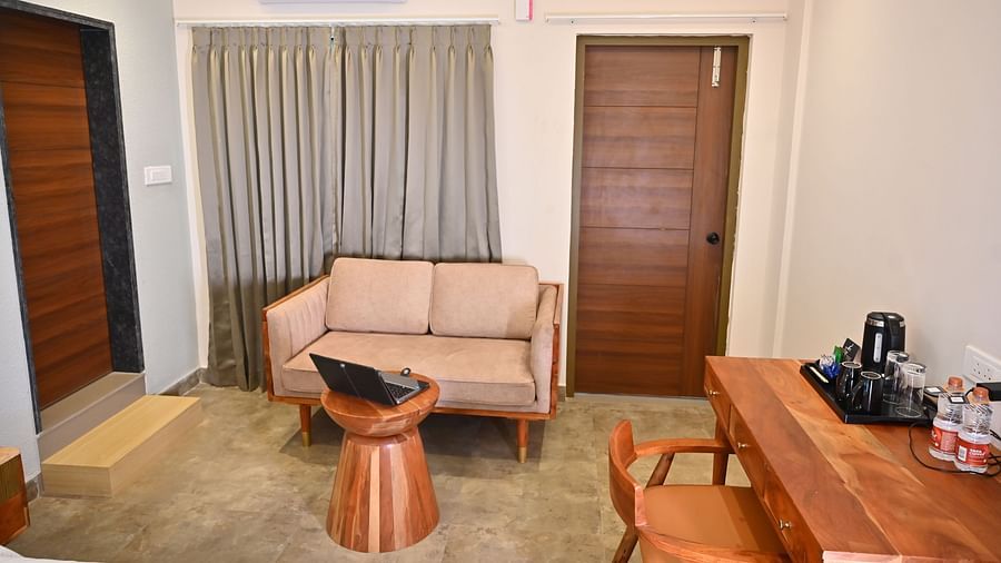 Cosy seating area in a room with a sofa, a wooden coffee table, a wooden desk with a chair, and a tea and coffee setup at TGI Livancia Hillside