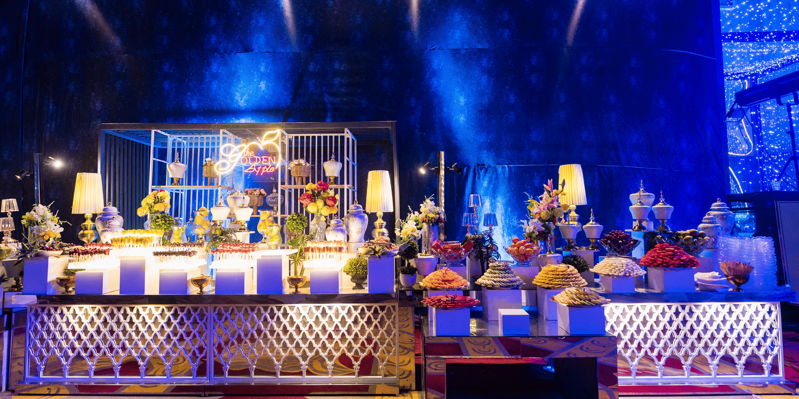 An elaborate bar or drinks service counter brightly lit with dramatic blue spotlights, featuring many bottles and glasses at Hotel Hukam's Lalit Mahal.