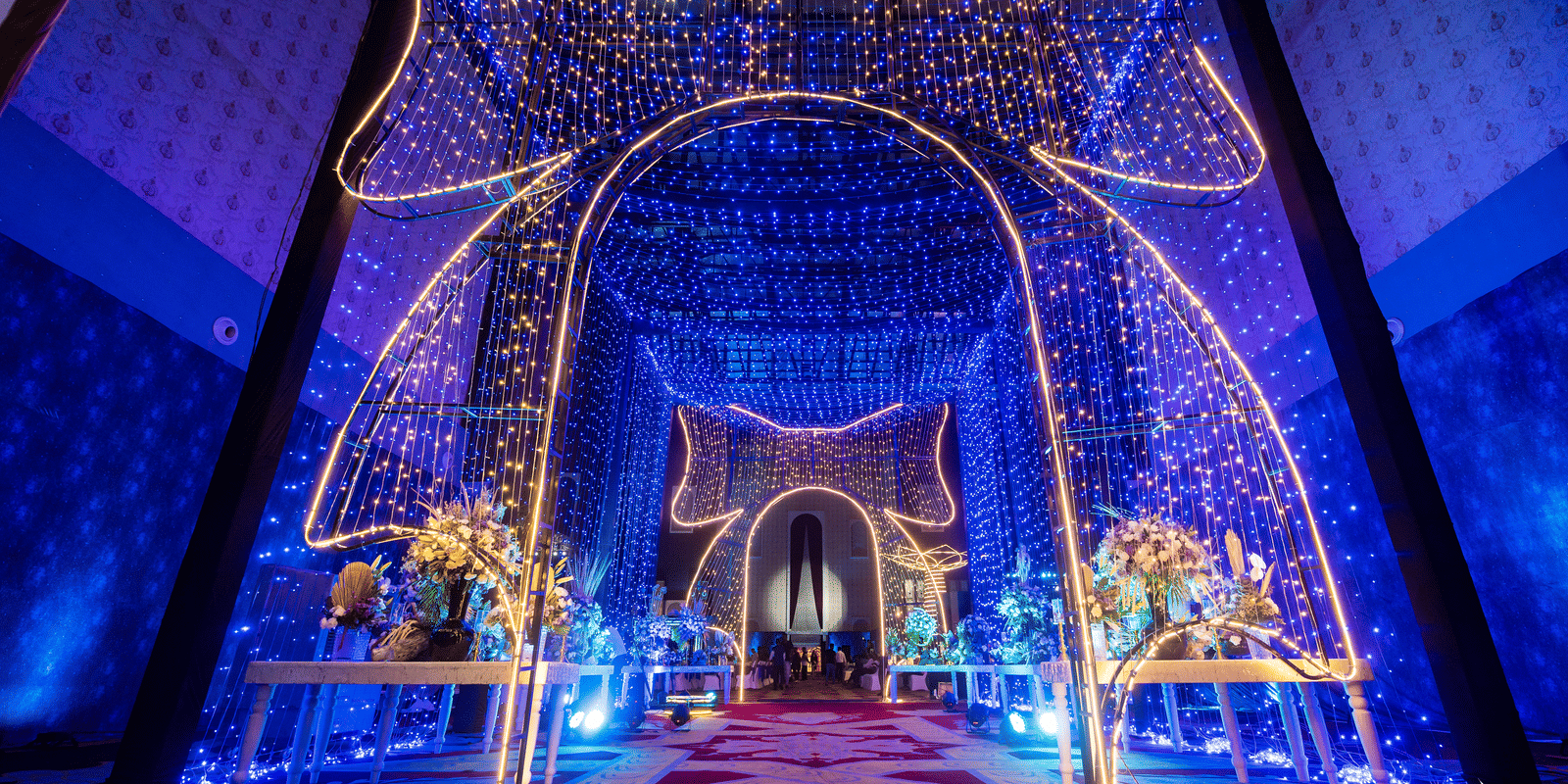 Brightly illuminated stage or entrance archway with elaborate blue and gold lighting and a sparkling curtain effect at Hotel Hukam's Lalit Mahal.