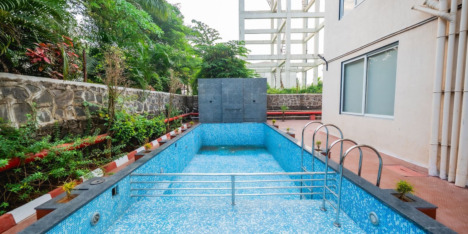 An outdoor swimming pool surrounded by greenery and a well-maintained pathway at Lotus Leaf Boutique Hotel.