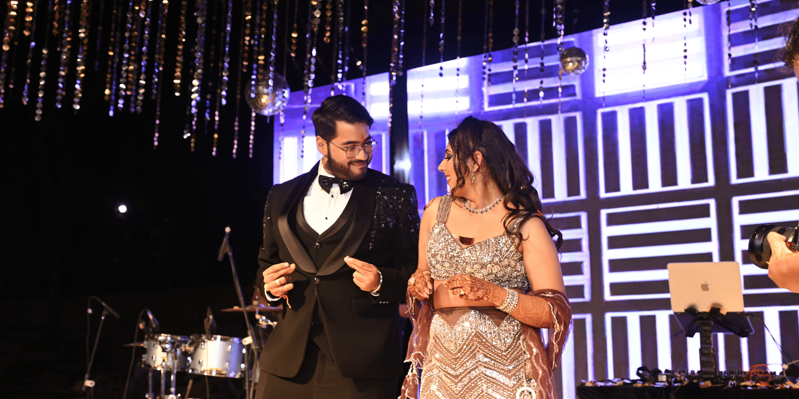  A happy couple on stage at a night event with disco balls and a band set up in the background - Megha Resort & Villas, Dehradun