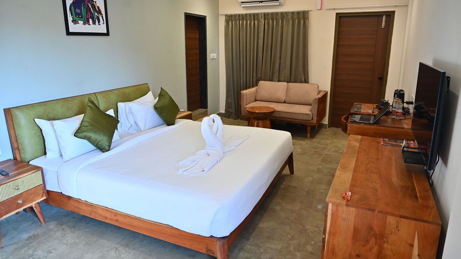 Spacious suite with a large bed, pillows, a sofa, and a wooden desk with modern amenities at TGI Livancia Hillside