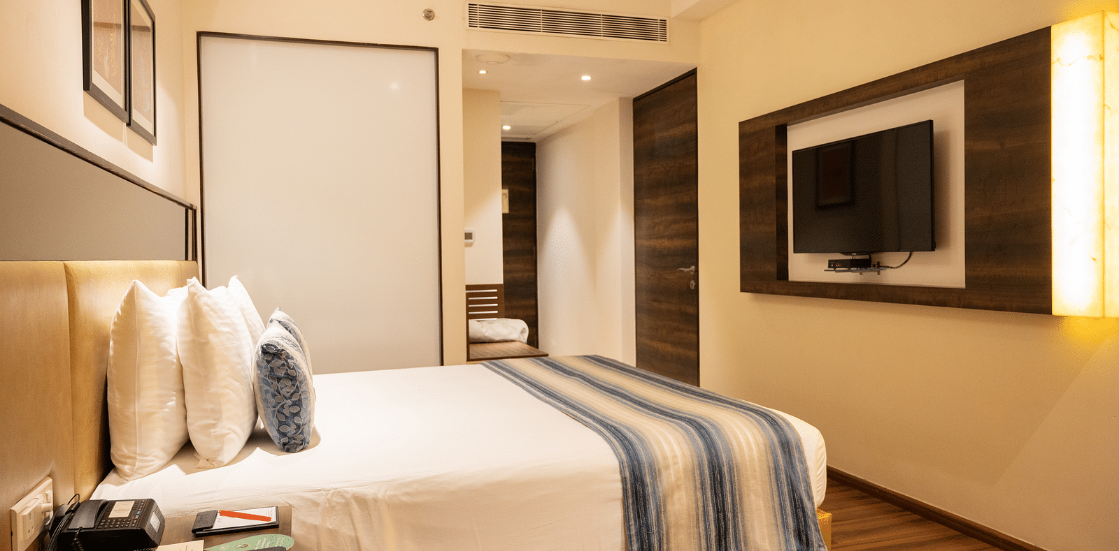 side view of a bedroom with a wall mounted television at Grand Kakinada by GRT Hotels