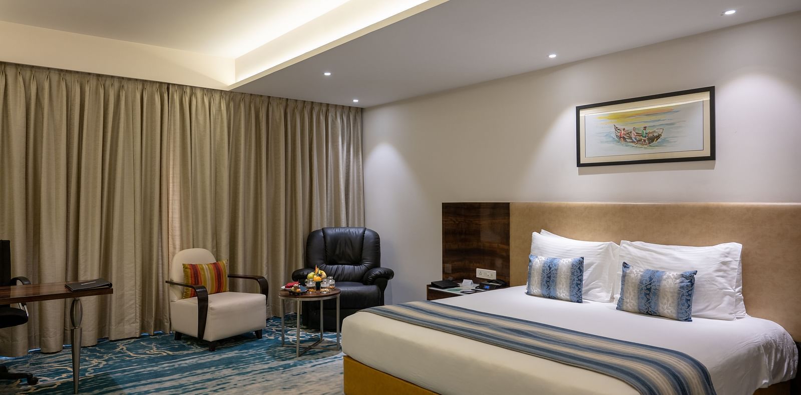 an image of a bedroom with a paining on top of the headboard at Grand Kakinada by GRT Hotels