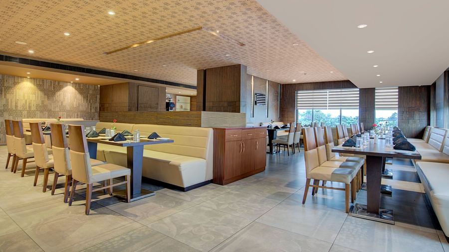 Chic dining area with booth seating and wooden interiors offering a warm and inviting atmosphere at Voyage Milestone Hotel and Banquet Siliguri