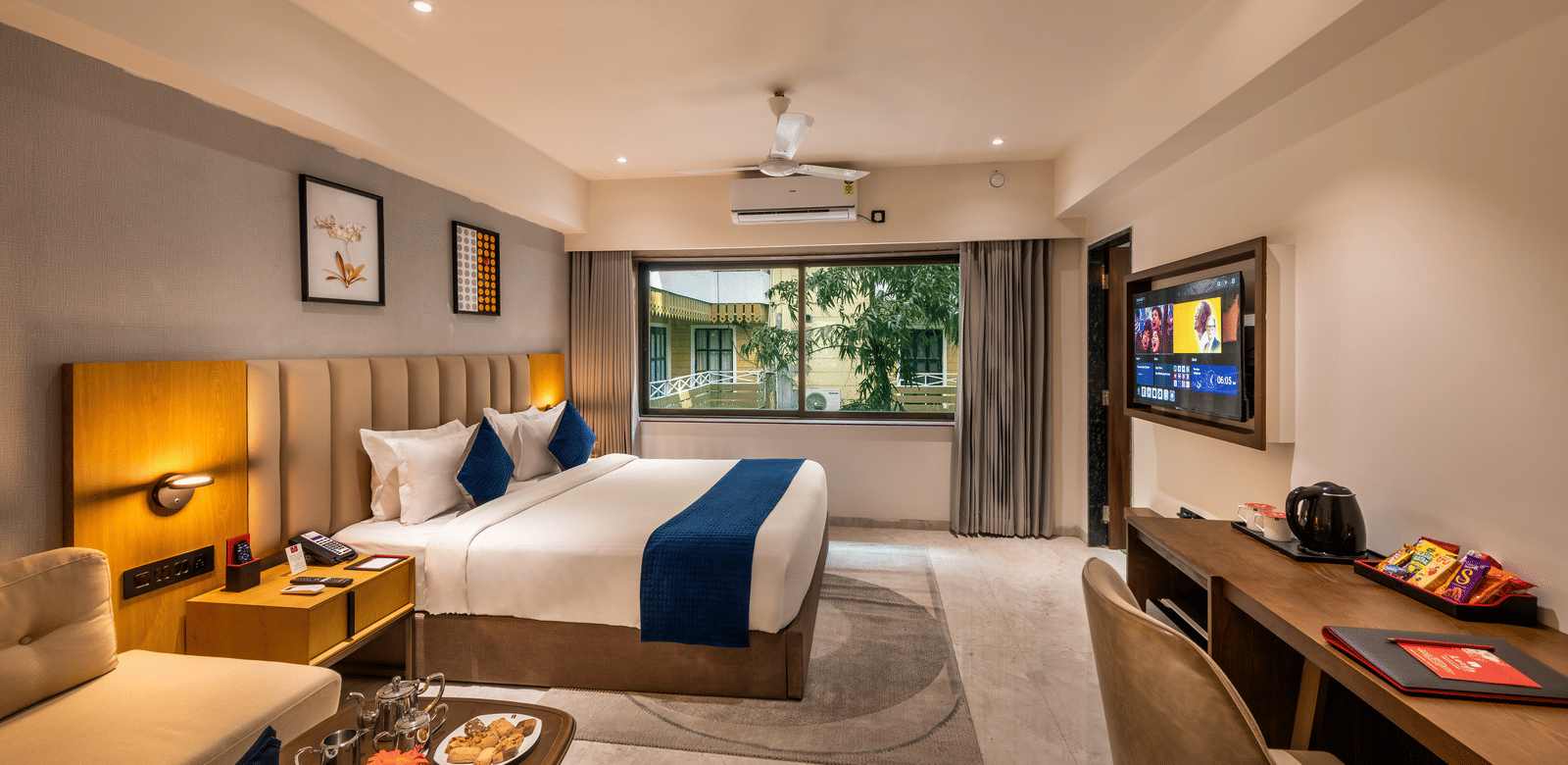 Comfortable stay space with large bed, work desk, and warm lighting at Lords Studio Inn, Jamnagar.