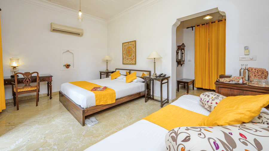 Bed with yellow throws and a seating area with yellow curtains in Aruna Vilas at Deo Bagh - 17th Century, Gwalior.