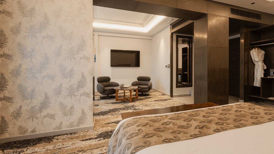 A luxury suite featuring a seating area with grey armchairs, a television, and a separate bedroom area at Ananta Express, Katra.