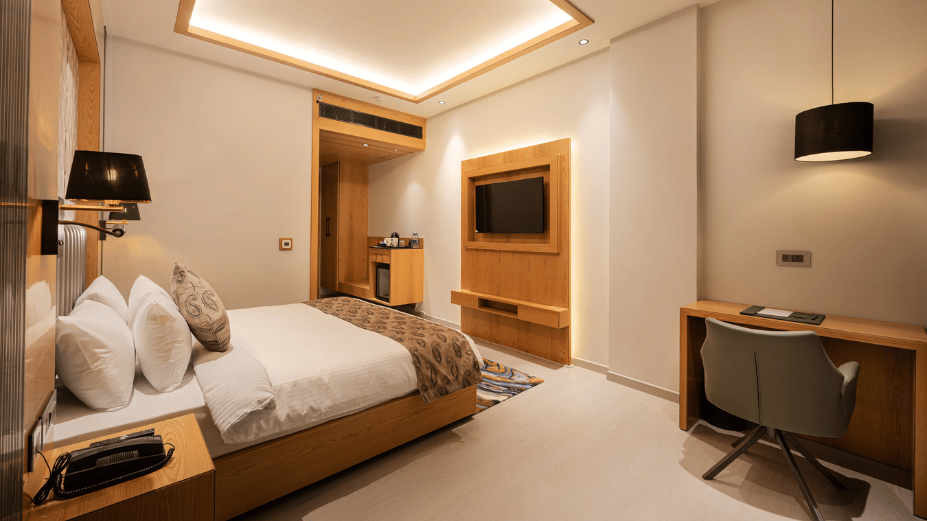 A modern guest room featuring a king-sized bed and a wooden wall unit with a mounted television at Ananta Express, Katra.