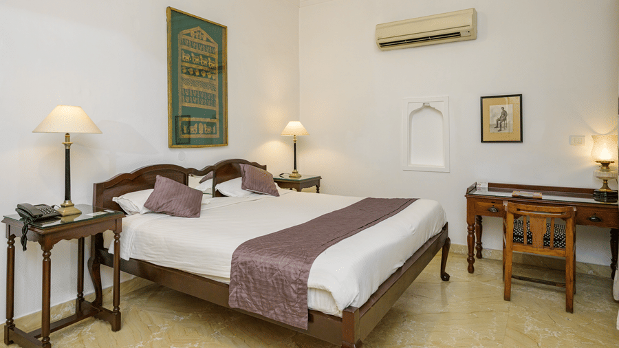 Bed with purple runner, wooden desk, and lamps in Samarjit Vilas at Deo Bagh - 17th Century, Gwalior.
