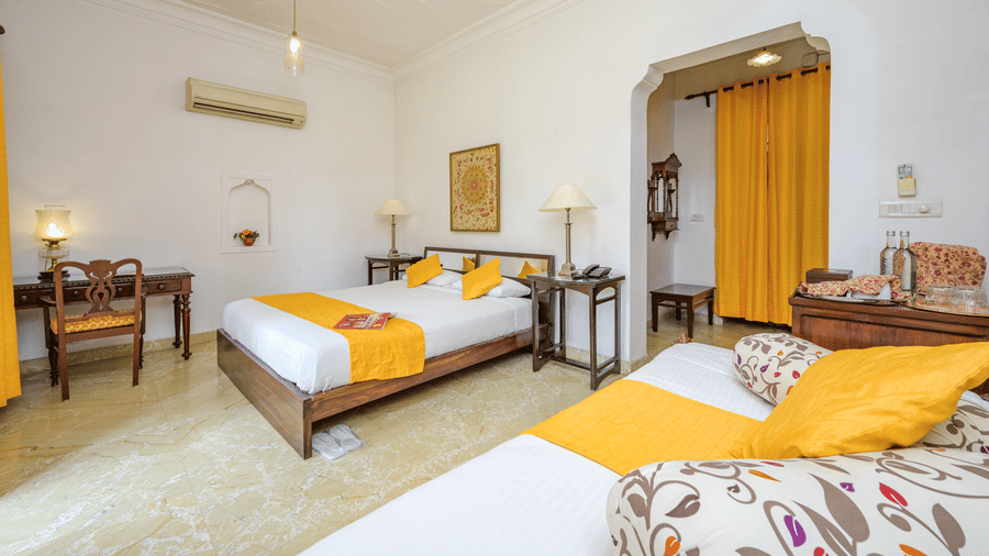 Bed with yellow throws and a seating area with yellow curtains in Aruna Vilas at Deo Bagh - 17th Century, Gwalior.