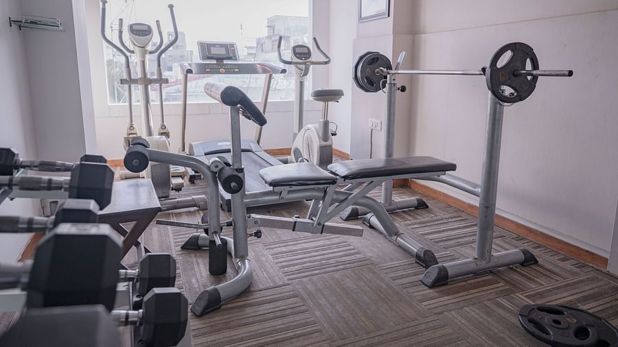 Compact gym with weights, bench press, and cardio equipment at Clarks Collection, Vadodara.