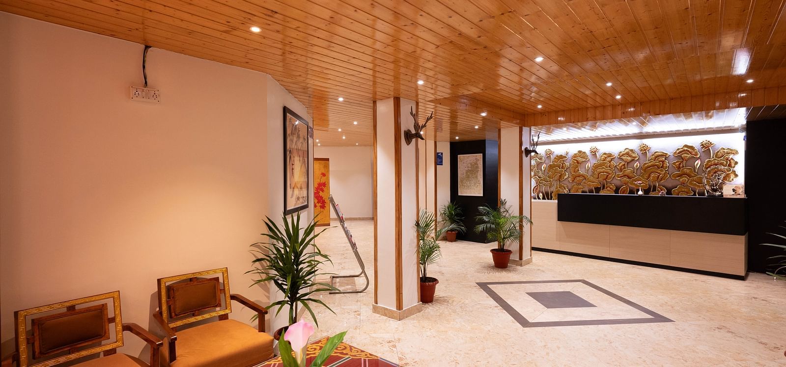 A lobby area with wooden interiors, vibrant decor, and a view of the reception desk at Avianna Hungry Jack, Gangtok.