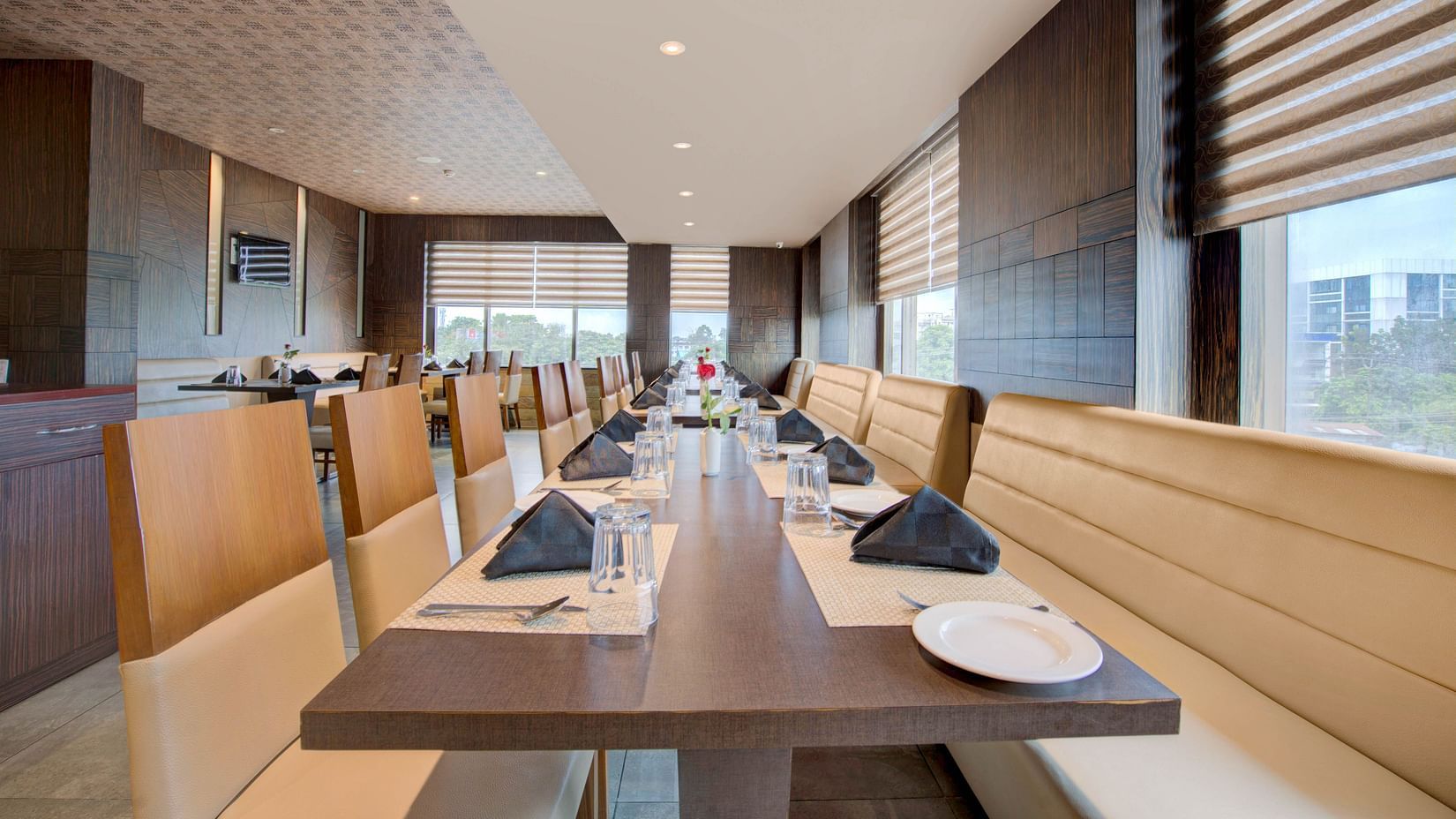 Well-arranged dining tables in a contemporary setting with large windows at Voyage Milestone Hotel and Banquet Siliguri