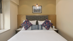 Superior Room at Hotel Le Grande featuring a queen size bed, white duvet, and decorative blue and red pillows