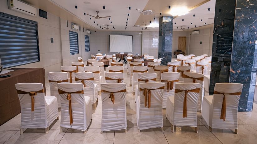 A hall with marble flooring, wooden tables, chairs, and a high ceiling at Clarks Collection Somnath.