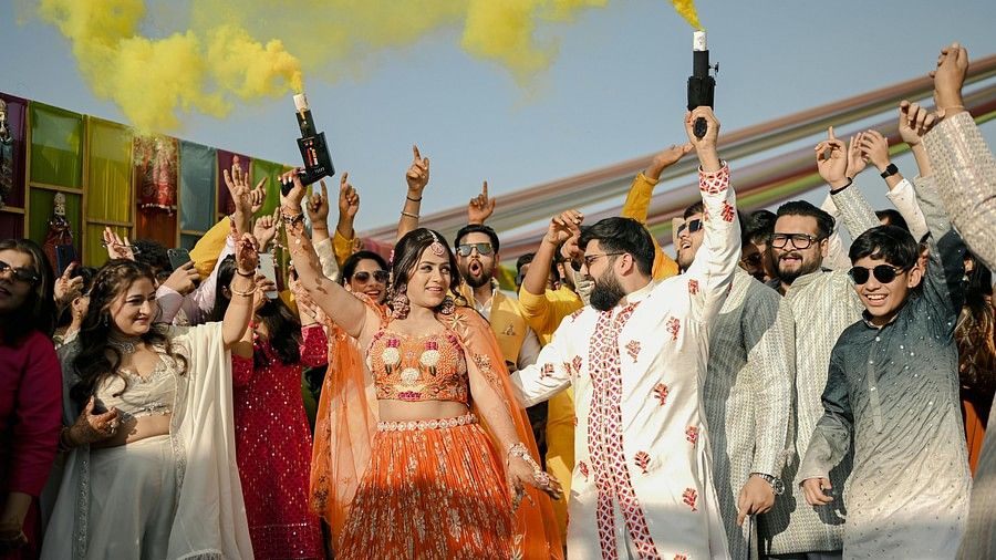 Bride and groom celebrating the haldi ceremony with colour popper with their friends and family.