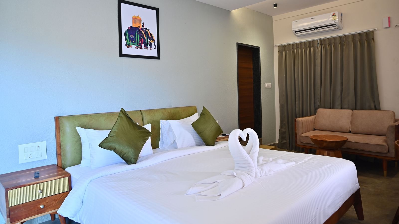 Club Suite featuring a large bed with pillows, a towel swan, a sofa, and warm wooden furniture at TGI Livancia Hillside