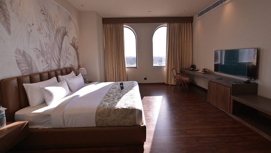 Suite with with a king size bed, a TV, and large windows. - Clarks Safari Haridwar