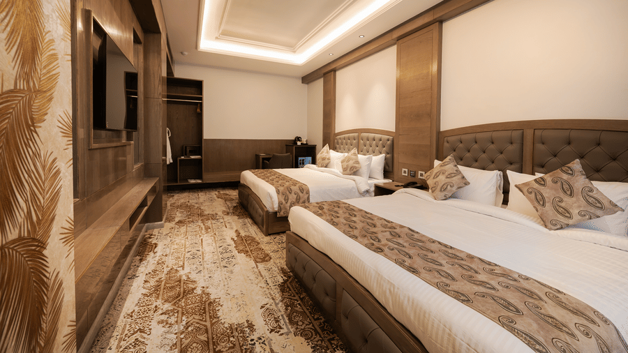 A guest room featuring two single beds with patterned headboards and modern wall-mounted television at Ananta Express, Katra.
