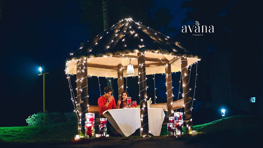 A gazebo or outdoor structure decorated with lights at night, with people sitting inside.