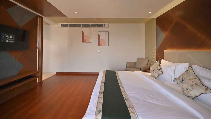 Side view of a bedroom featuring two portraits hanging on the wall above at Clarks Collection Grand Sapphire, Ajmer.