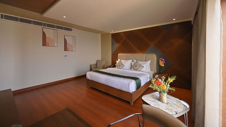 Front view of a bedroom with a table beside the bed, holding a flower vase Clarks Collection Grand Sapphire, Ajmer. 