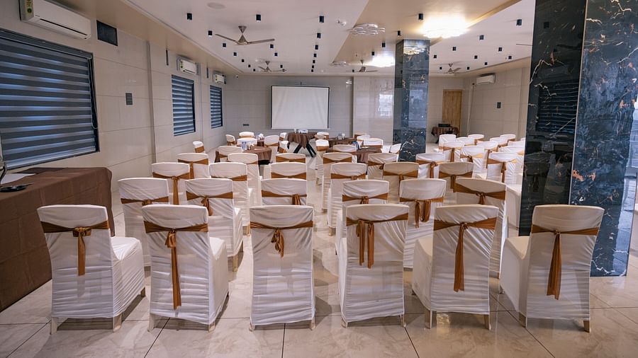 A hall with marble flooring, wooden tables, chairs, and a high ceiling at Clarks Collection Somnath.