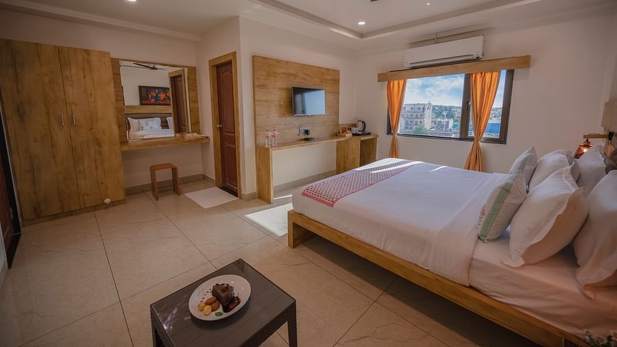A room with double bed, tv, wardrobe, dressing area, and city view window at Clarks Collection, Somnath.
