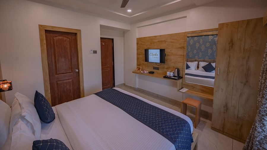 A room featuring a double bed, wall-mounted tv, and wooden decor at Clarks Collection, Somnath.