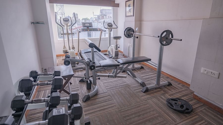 Compact gym with weights, bench press, and cardio equipment at Clarks Collection, Vadodara.