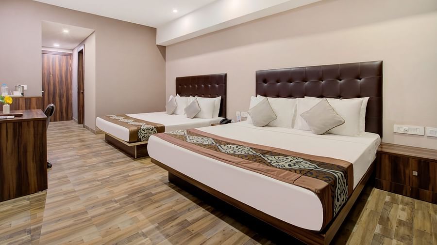 Twin-bed room with plush bedding, reading lamps, and a warm-toned interior at Voyage Milestone Hotel and Banquet Siliguri