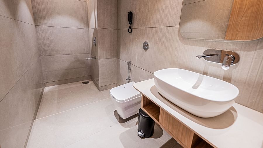 A spacious washroom with a washbasin and a mirror above it, with a shower area towards the end at Indie Stays Mumbai International Airport.