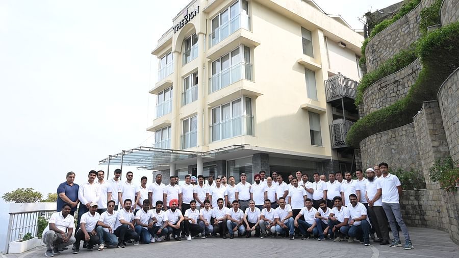 A large group in matching 'Refex' shirts poses for a photo outside The Zion hotel.