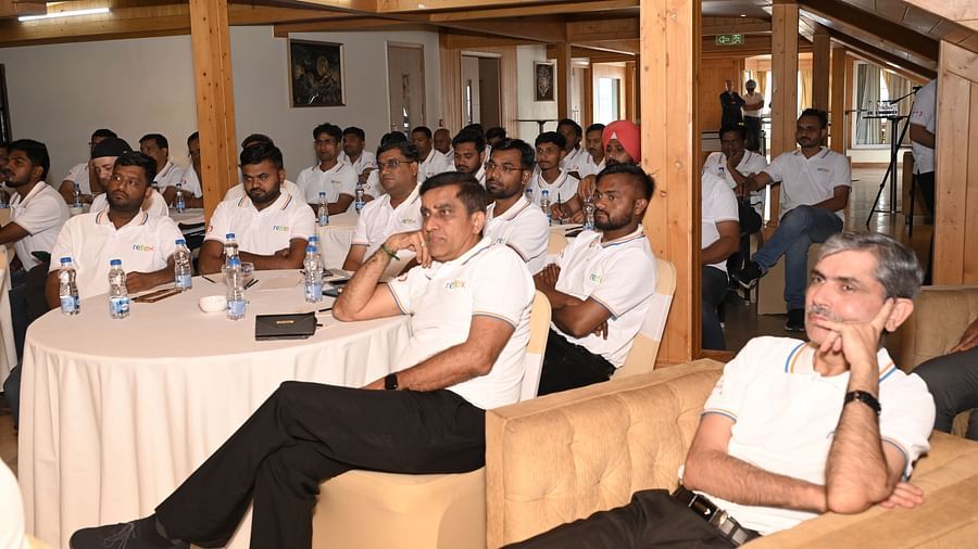 Employees in matching 'Refex' shirts attend a focused session in a wooden conference room - The Zion, Shimla.