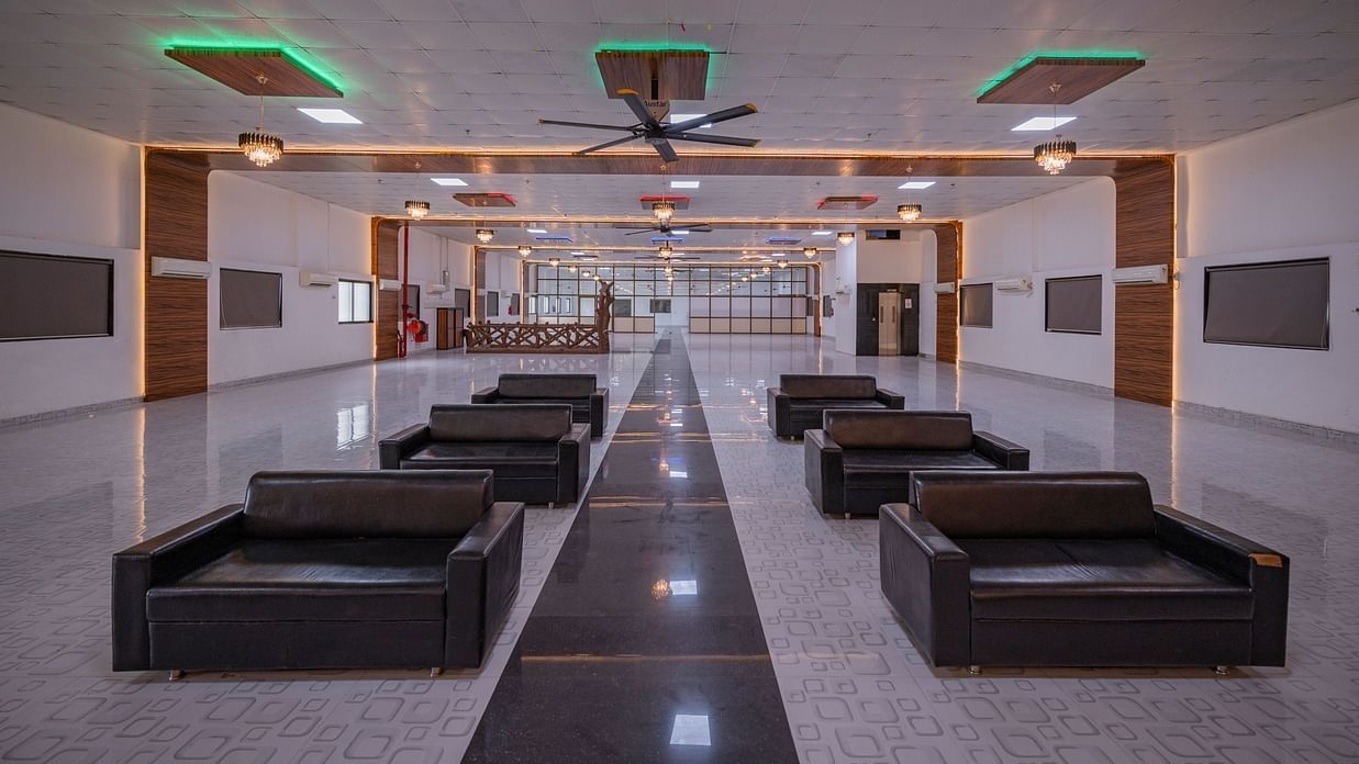 A long, open hall at Clarks Safari Kheda, set up with numerous seating arrangements, leading towards an exit.