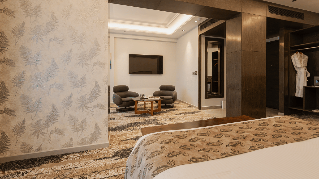 A luxury suite featuring a seating area with grey armchairs, a television, and a separate bedroom area at Ananta Express, Katra.