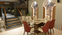 Round dining table with cushioned chairs and artistic wall designs at Pride Elite Raipur.