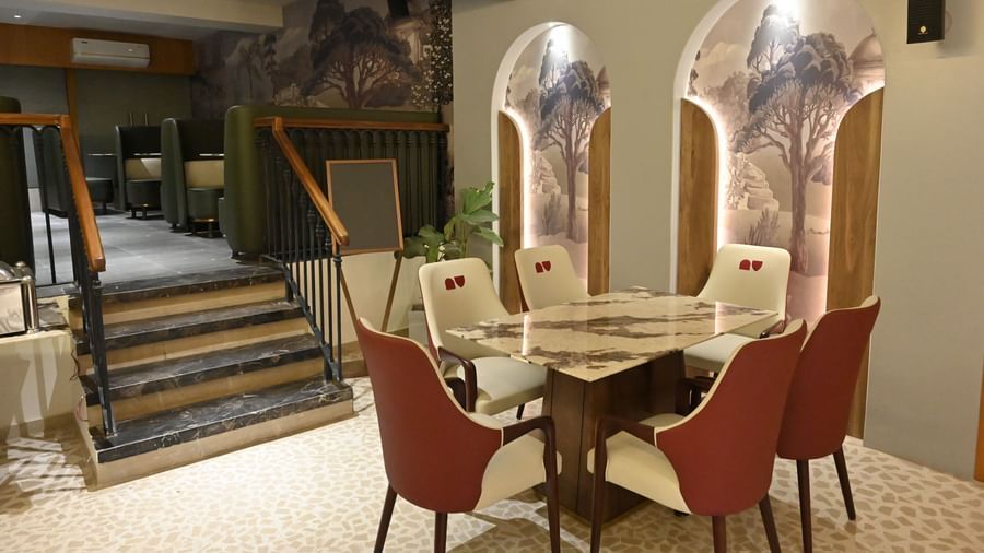Round dining table with cushioned chairs and artistic wall designs at Pride Elite Raipur.