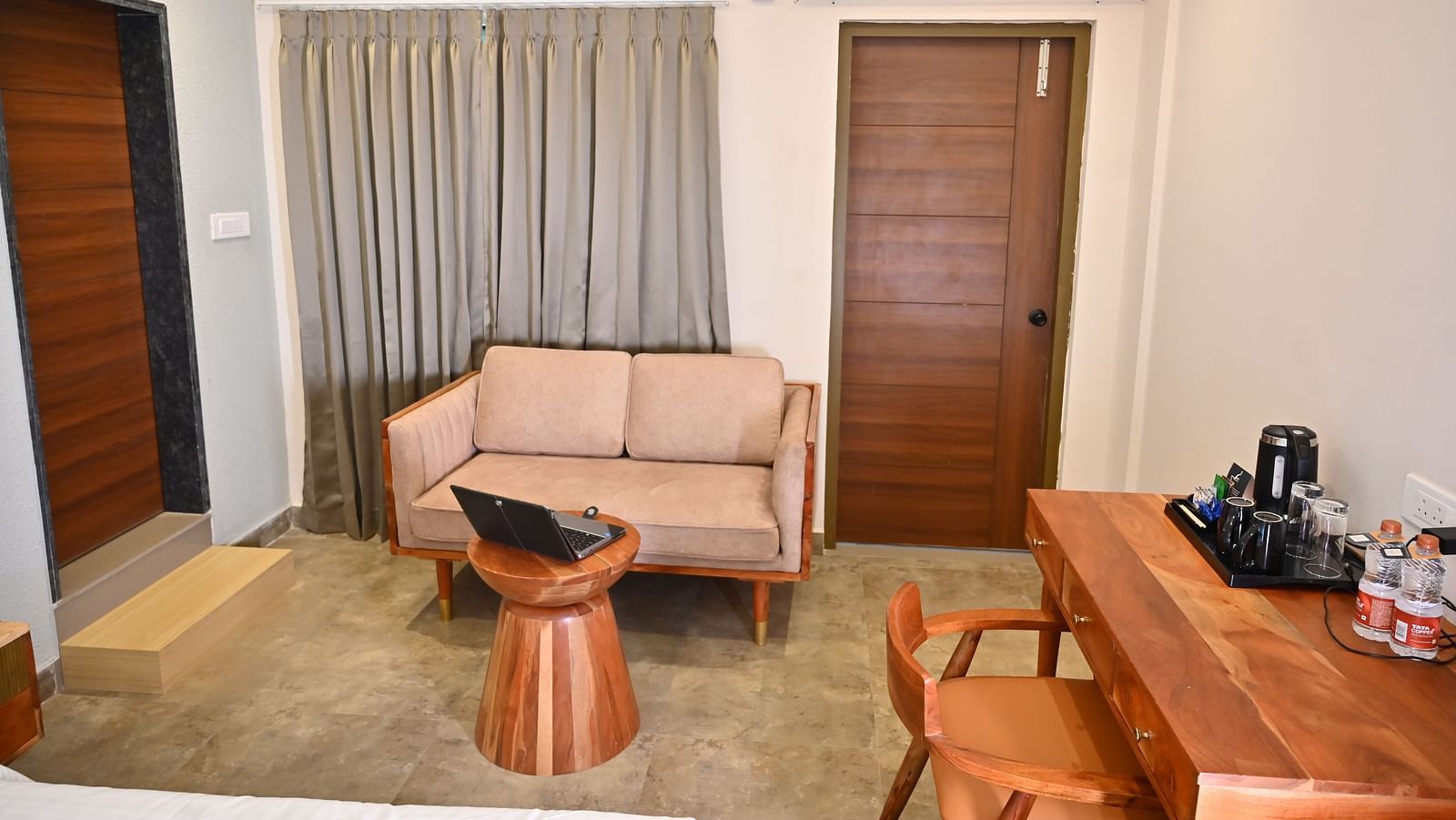 Cosy seating area in a room with a sofa, a wooden coffee table, a wooden desk with a chair, and a tea and coffee setup at TGI Livancia Hillside