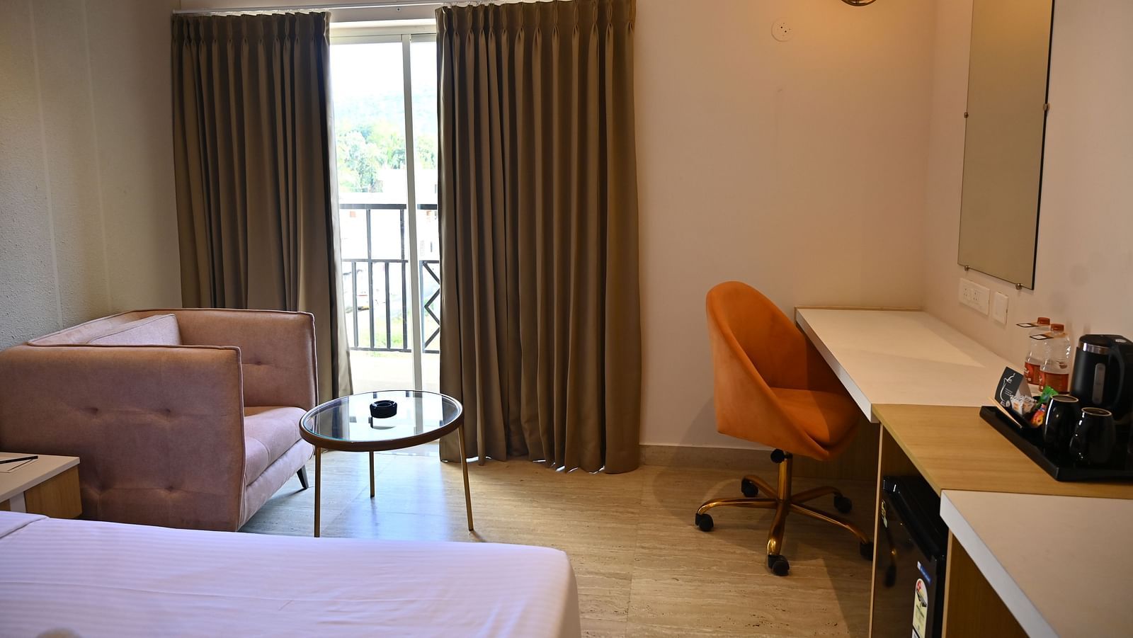 Premium room corner with a chair, a small glass table, and a desk near a sliding door that opens to a private balcony at TGI Livancia Hillside